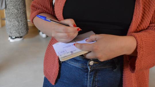 persona escrivint postal a la seva veïna